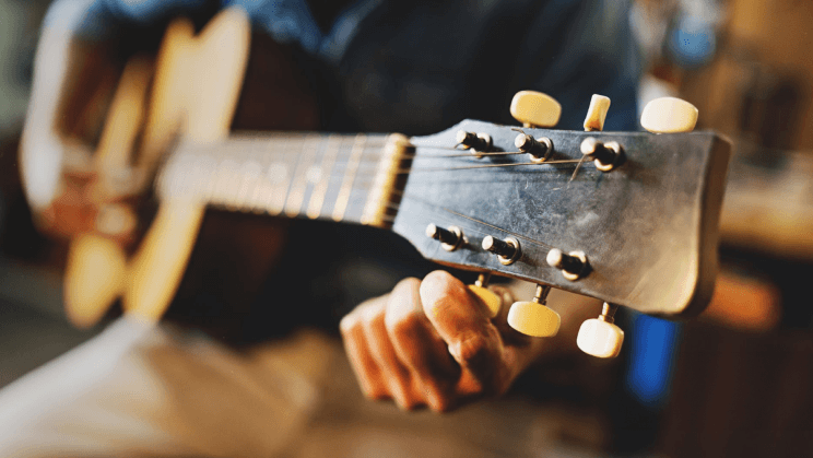person tuning a guitar